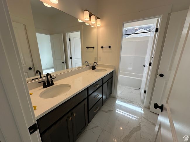 Bathroom featuring double vanity, marble finish floors, and shower / tub combination | Image 21