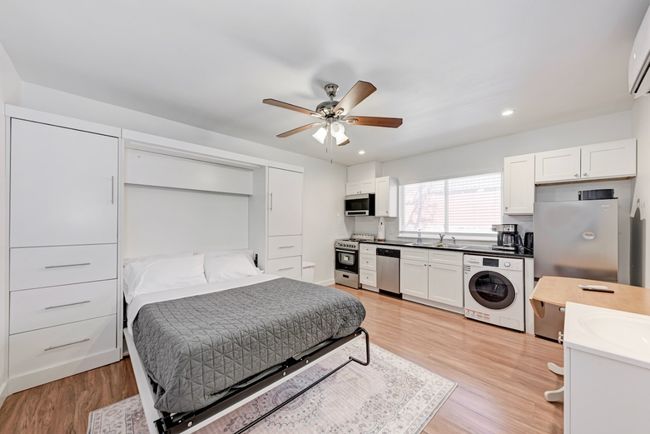 Bedroom featuring washer / dryer, light wood-type flooring, recessed lighting, a wall unit AC, and ceiling fan | Image 5