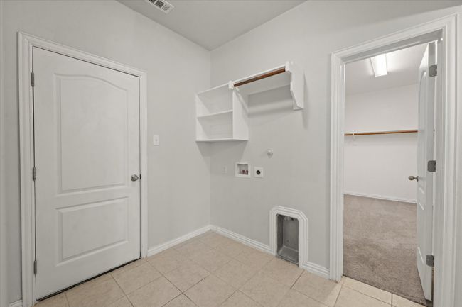 Laundry room with open storage and access to the primary closet. | Image 19