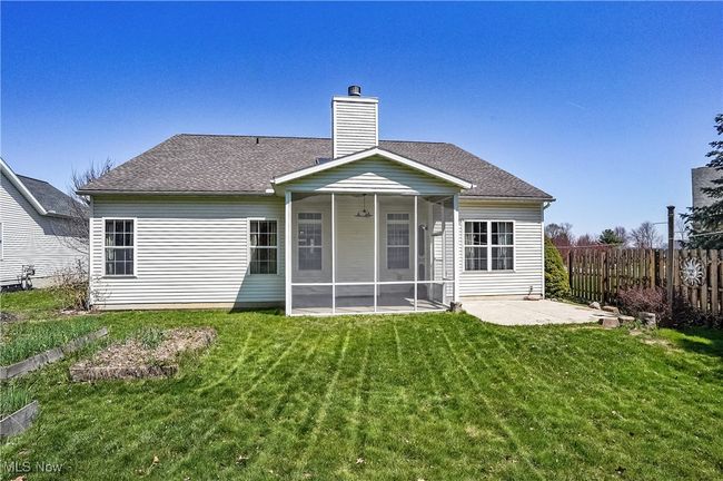 Rear view of property with a chimney, fence, a lawn, a sunroom, and a patio | Image 48
