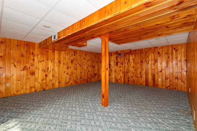 Basement with carpet flooring, a paneled ceiling, and wood walls | Image 30