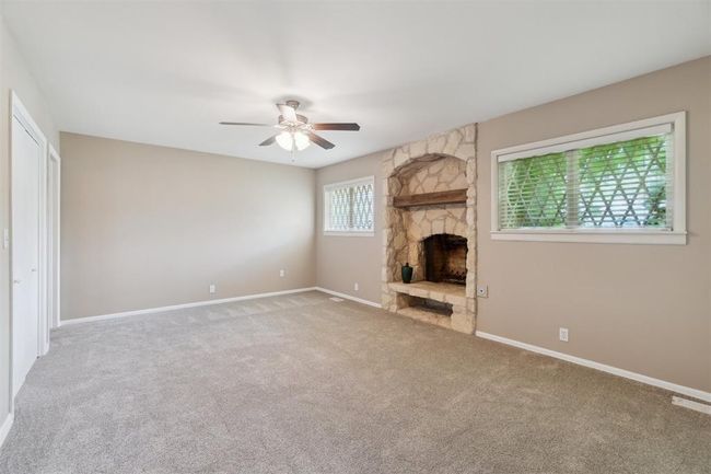 Unfurnished living room featuring ceiling fan, a fireplace, and carpet flooring | Image 26