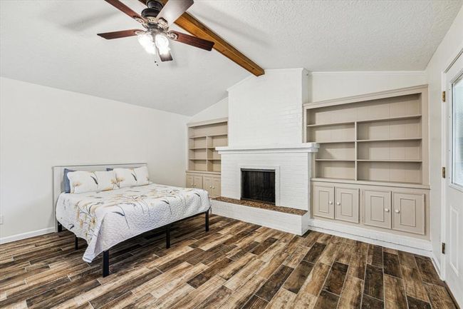 The secondary ensuite bedroom is a cozy retreat, especially with the addition of a wood-burning fireplace. Surrounding the fireplace with wall-to-wall cabinetry not only maximizes storage space but also adds visual interest and functionality to the room | Image 26