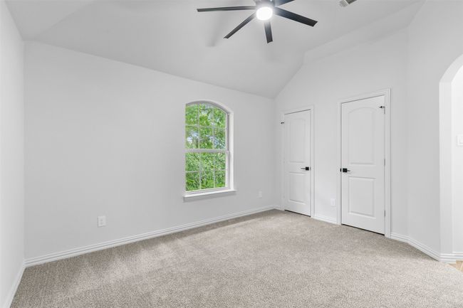 Unfurnished bedroom with arched walkways, vaulted ceiling, carpet, and baseboards | Image 35