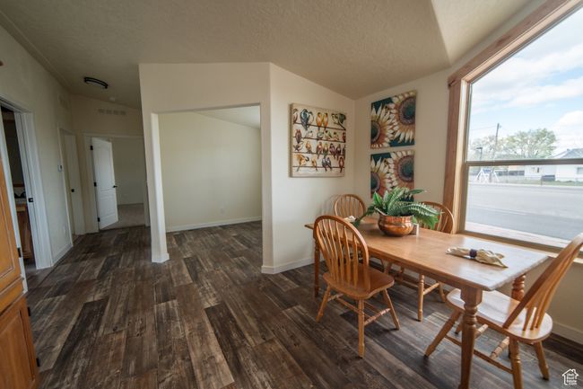 Dining space featuring dark wood finished floors, vaulted ceiling, a textured ceiling, and visible vents | Image 10
