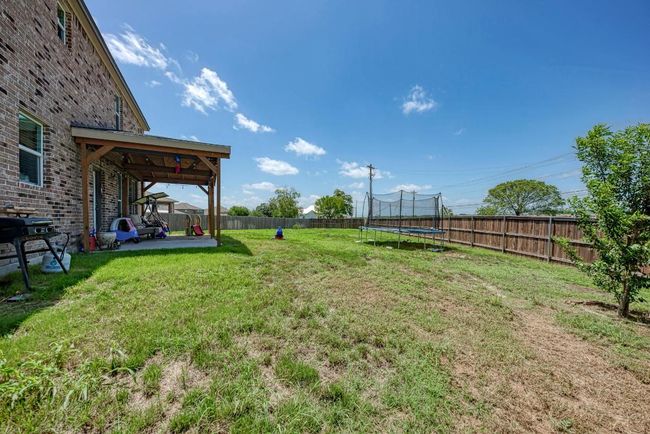 Fenced backyard featuring a trampoline and a patio | Image 35