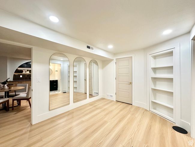 Basement with light wood finished floors, built in shelves, recessed lighting, and arched walkways | Image 35
