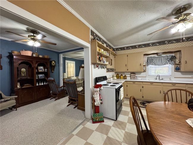 Kitchen featuring electric range, open shelves, ceiling fan, ornamental molding, and a textured ceiling | Image 20