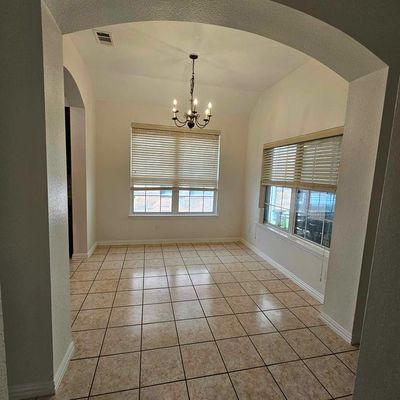 Tiled empty room featuring a healthy amount of sunlight, vaulted ceiling, and a notable chandelier | Image 3