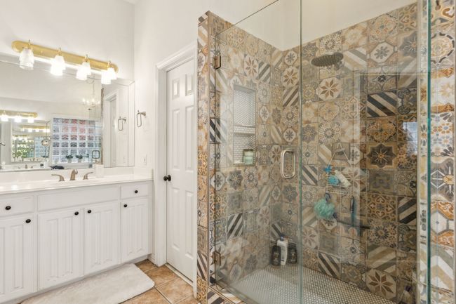 Bathroom with a shower stall, tile patterned flooring, vanity, and a chandelier | Image 21