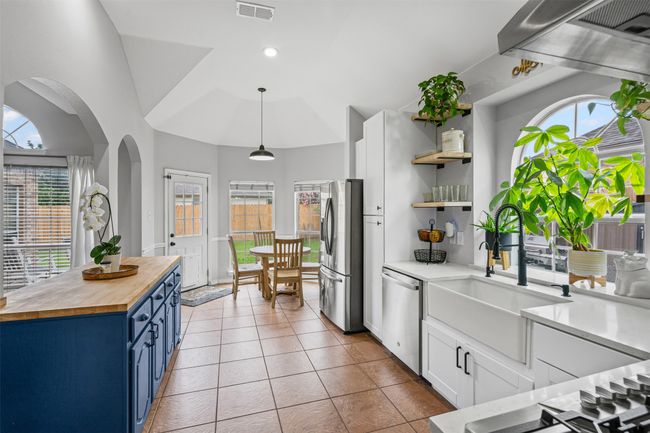 Kitchen featuring wood counters, blue cabinetry, appliances with stainless steel finishes, arched walkways, and white cabinets | Image 14