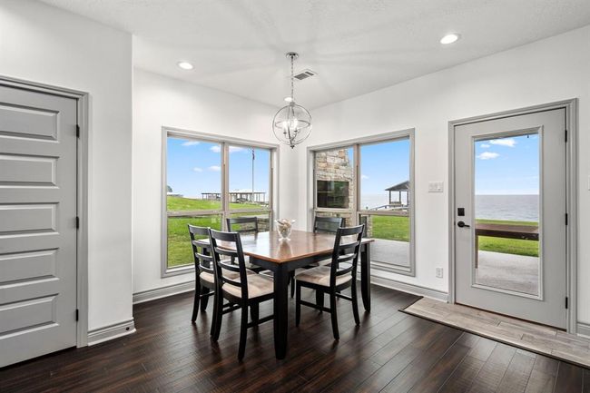 Home features rich dark wood floors w/ beautiful views of the lake through the breakfast room. | Image 6