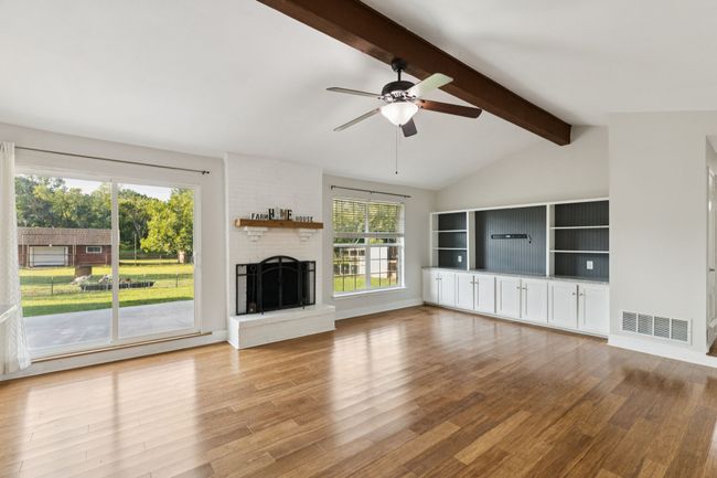 Unfurnished living room with wood finished floors, a ceiling fan, and a brick fireplace | Image 8