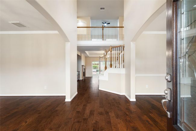 This inviting entry showcases an open-concept layout with high ceilings, a grand staircase, and spacious rooms on both sides. | Image 6