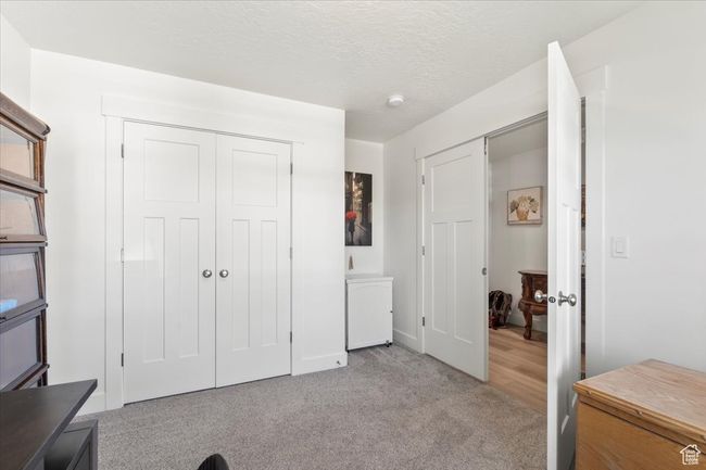 Bedroom with light colored carpet, baseboards, a closet, and a textured ceiling | Image 20