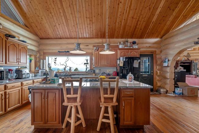 Kitchen featuring rustic walls, black fridge, wooden ceiling, lofted ceiling, and light wood finished floors | Image 32