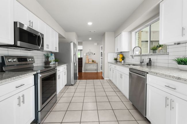 Kitchen featuring appliances with stainless steel finishes, a sink, backsplash, white cabinets, and recessed lighting | Image 23