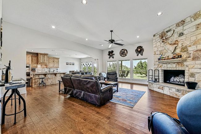 Living room with arched walkways, dark wood-style flooring, ceiling fan, recessed lighting, and a fireplace | Image 8