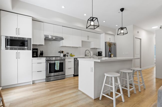 Kitchen with a sink, light wood-type flooring, appliances with stainless steel finishes, under cabinet range hood, and backsplash | Image 4