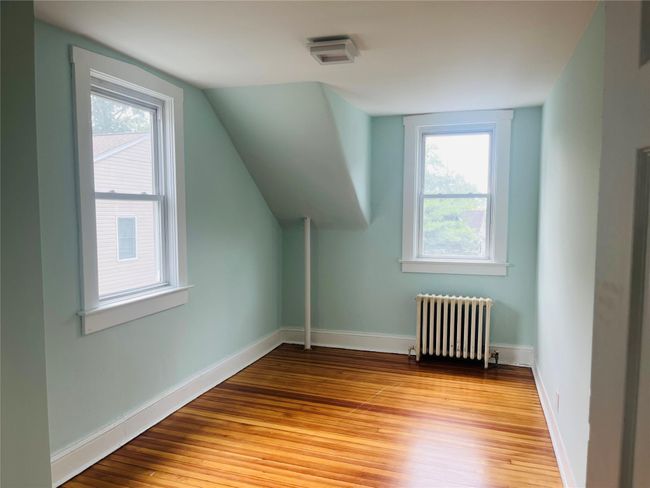 Bonus room featuring radiator heating unit, wood finished floors, healthy amount of natural light, and vaulted ceiling | Image 13