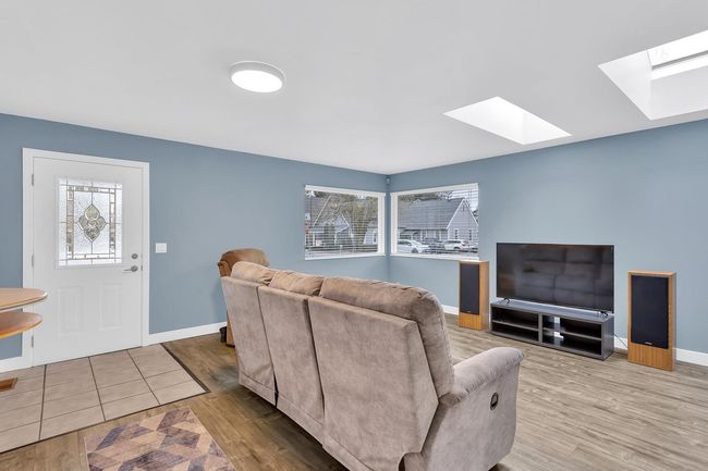 Living area featuring a skylight, baseboards, and wood finished floors | Image 6
