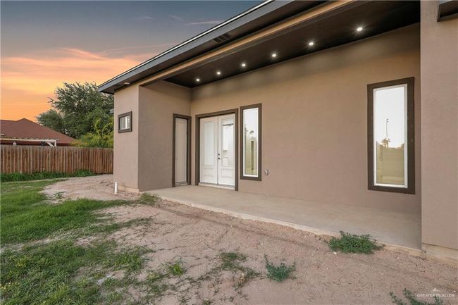 Side of property at dusk featuring a patio, stucco siding, and fence | Image 5