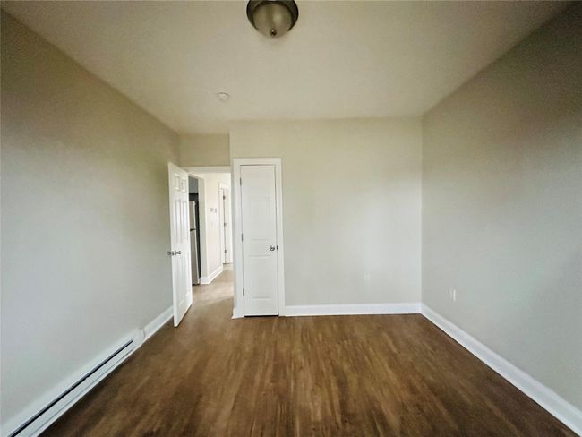 Empty room featuring a baseboard radiator and dark hardwood / wood-style floors | Image 6