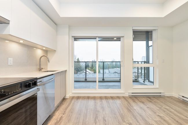 Kitchen featuring electric range oven, baseboard heating, stainless steel dishwasher, a sink, and light wood finished floors | Image 4