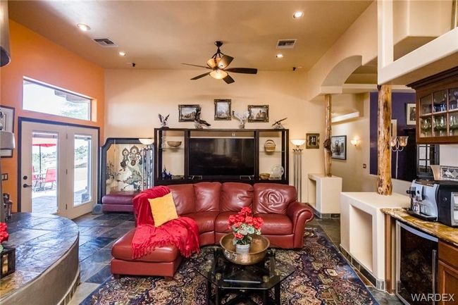 Living area featuring arched walkways, stone tile flooring, ceiling fan, recessed lighting, and wine cooler | Image 42