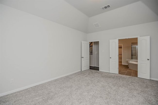 Unfurnished bedroom with carpet floors, a walk in closet, lofted ceiling, baseboards, and visible vents | Image 17