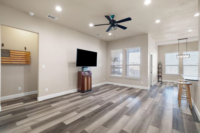 Unfurnished living room with baseboards, recessed lighting, wood finished floors, and ceiling fan with notable chandelier | Image 5