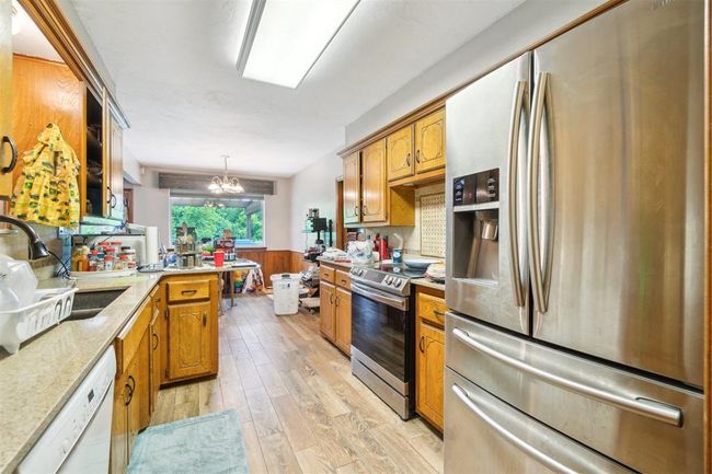 Kitchen with stainless steel appliances, light wood-type flooring, a wainscoted wall, a chandelier, and a peninsula | Image 15
