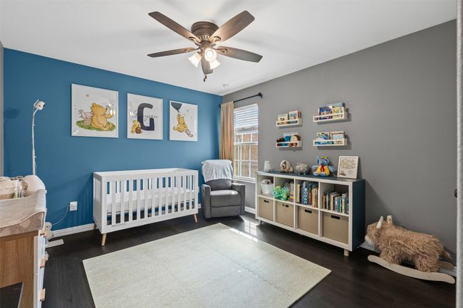 Bedroom featuring wood finished floors, a crib, baseboards, and a ceiling fan | Image 7