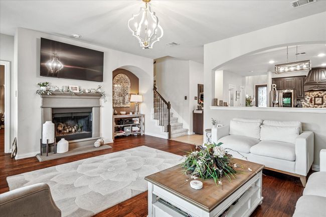 Living area with arched walkways, wood finished floors, a fireplace with raised hearth, and recessed lighting | Image 11
