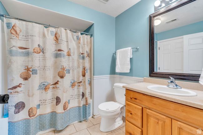 Bathroom featuring wainscoting, tile patterned floors, vanity, and curtained shower | Image 12