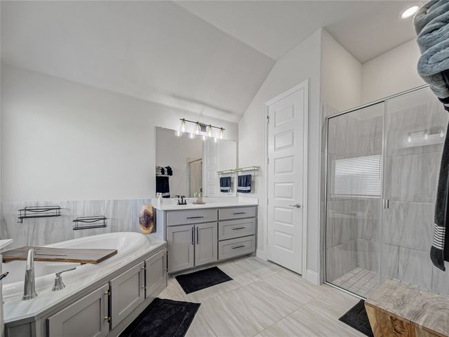 Bathroom featuring vanity, a garden tub, a stall shower, and lofted ceiling | Image 22