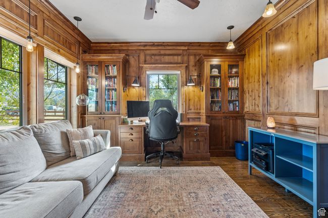 Home office with dark wood-type flooring, ceiling fan, and wood walls | Image 25