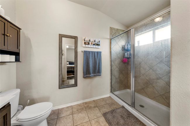 Full bath featuring vaulted ceiling, a shower stall, tile patterned floors, and vanity | Image 14