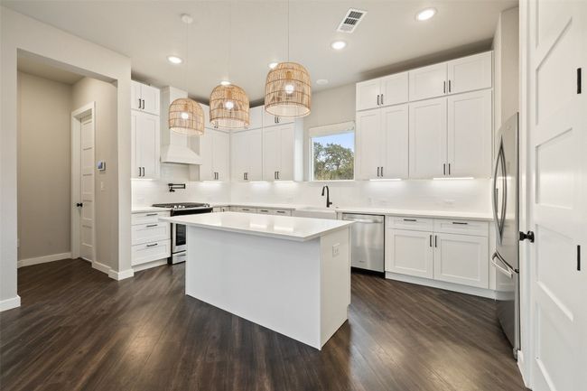 Kitchen with pendant lighting, white cabinetry, decorative backsplash, and stainless steel appliances | Image 11