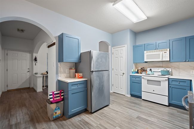 The heart of the home is a beautiful kitchen with wrap around counters, custom cabinet color, electric stove, microwave, and recent refrigerator with is included. | Image 9