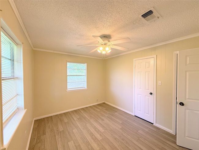 Spare room with a textured ceiling, ornamental molding, light wood-type flooring, and ceiling fan | Image 16