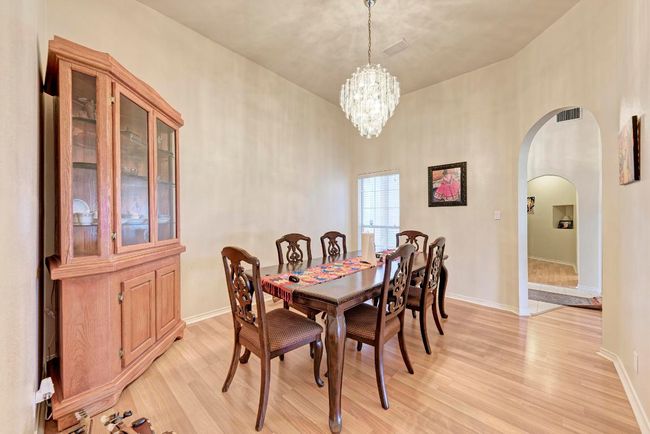 Dining room featuring arched walkways, light wood-style flooring, a chandelier, baseboards, and a towering ceiling | Image 16