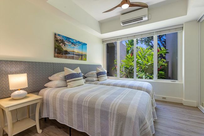 The light-filled second bedroom features a plethora of tall windows facing lush tropical landscaping | Image 22
