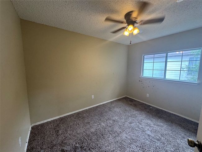 Carpeted empty room featuring a ceiling fan, a textured ceiling, and baseboards | Image 4