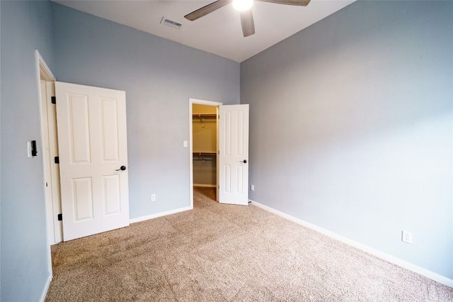 Bedroom with carpet floors, a walk in closet, a closet, baseboards, and a high ceiling | Image 25