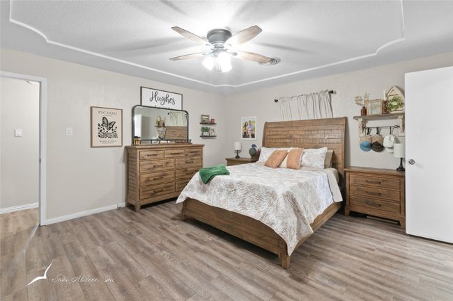 Bedroom featuring baseboards, a textured ceiling, and wood finished floors | Image 14