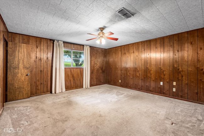 Carpeted empty room with ceiling fan and wooden walls | Image 17