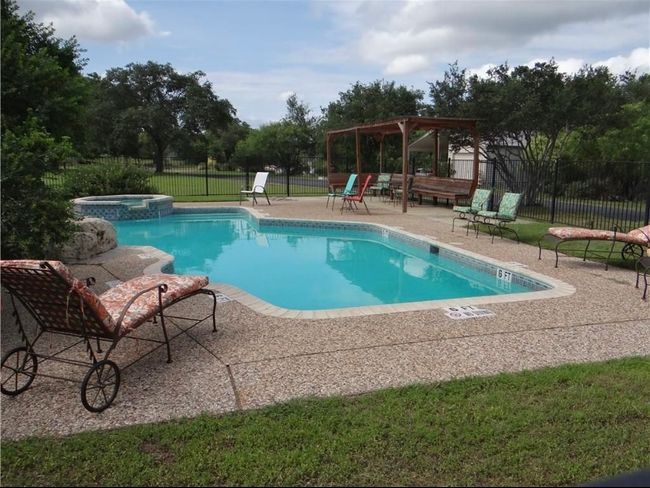 View of pool with a patio area, fence, a pool with connected hot tub, and view of scattered trees | Image 7