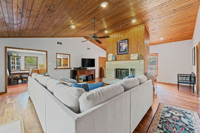 A cozy stacked stone fireplace is the center point of the living room and across from it is a wall of sliders that overlook the back patio and yard. | Image 5