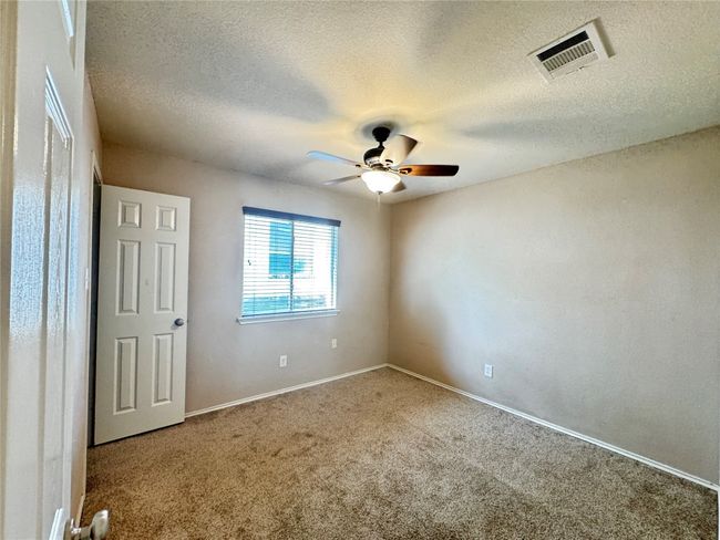 Carpeted empty room featuring a ceiling fan and a textured ceiling | Image 20